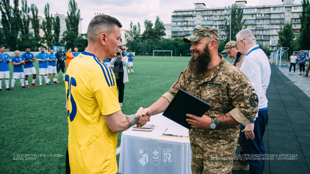 Військовий вручає нагороду учаснику благодійного футбольного матчу