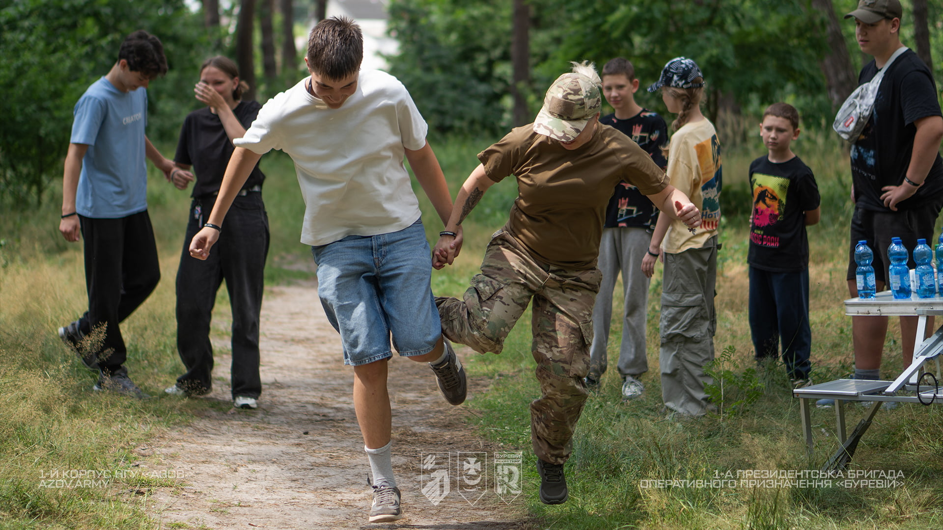 Підлітки проходять смугу перешкод разом із військовослужбовицею 1-ї Президентської бригади «Буревій» під час військово-патріотичного вишколу
