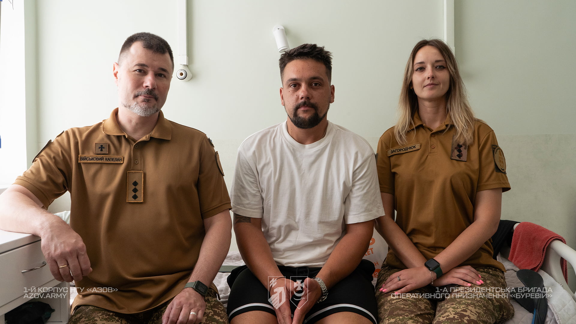 Військовий капелан і військовослужбовиця з пораненим бійцем у лікарняній палаті